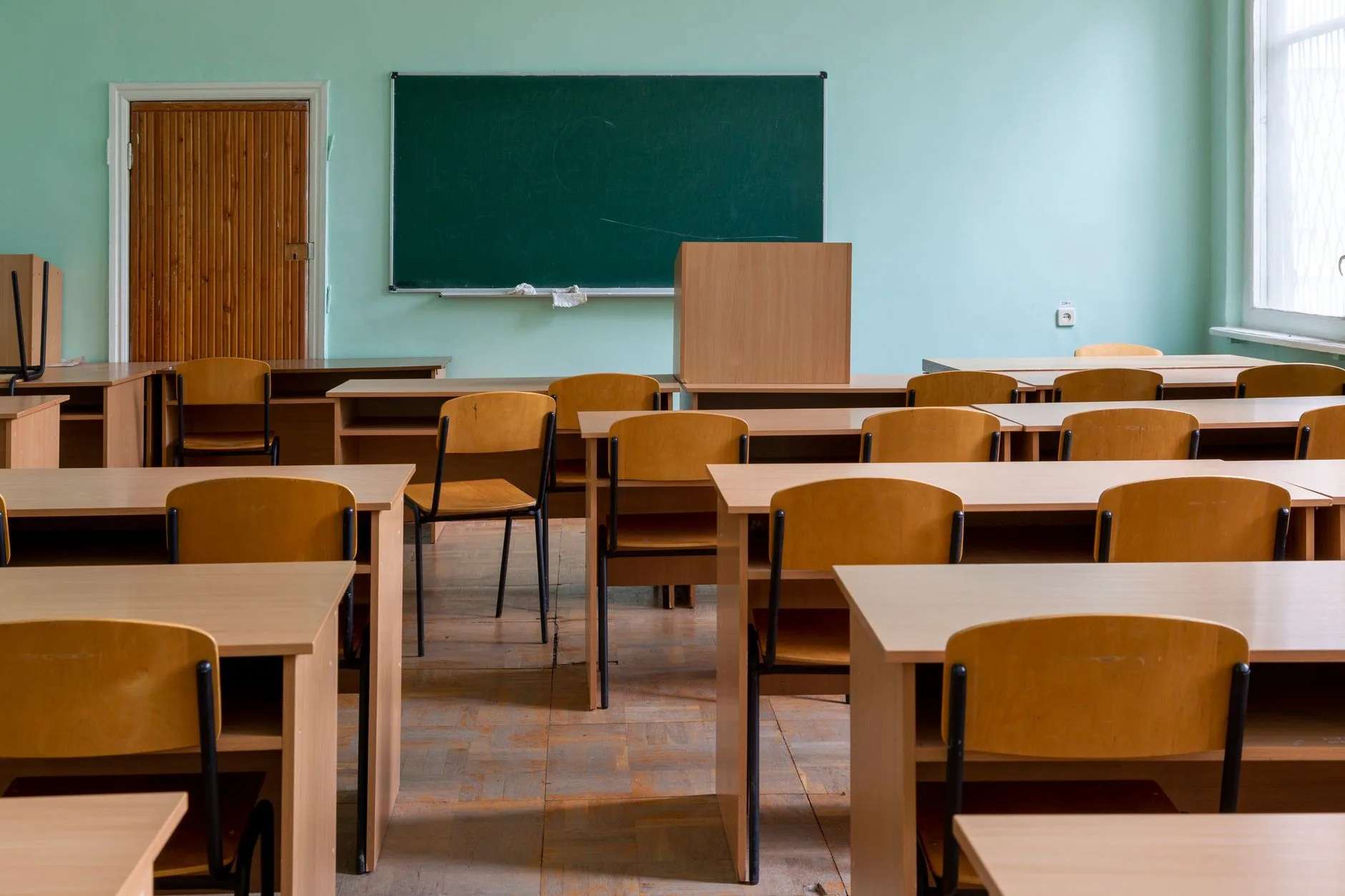 Miljöbild – classroom with wooden desks and a green board